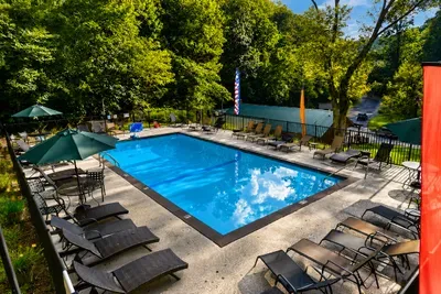 Relax and unwind at the community outdoor swimming pool with comfortable lounge seating and scenic forest views.