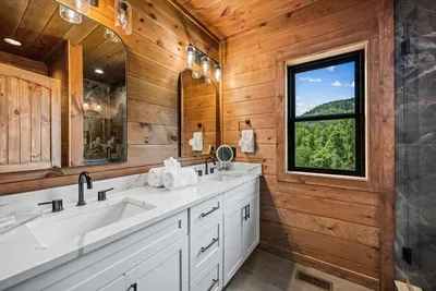 Double vanity with a forest view over the sink. Fresh towels, real counter space, and mountain light to start the day on.