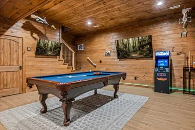 Full game room: pool table, arcade cabinet, cue rack, and actual space to take a shot. Winner stays on.