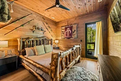 Handcrafted log bed frame, pine walls, and a window looking into the treetops. Rustic done properly.