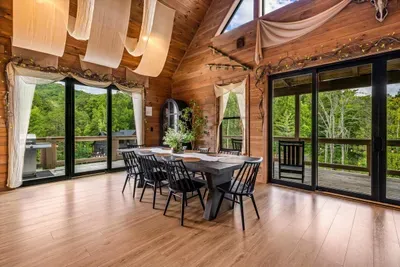 A dining table sized for the whole group with a wall of glass behind it. Mountain views with breakfast, sunset light with dinner.
