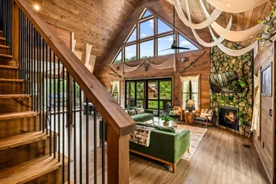Fireplace lit, staircase open to the vaulted great room above. Come down in the morning and this whole space is already full of light.