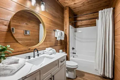 Full bath with a tub-shower combo, round mirror, and fresh linens stacked and ready. Family-ready and easy to share.