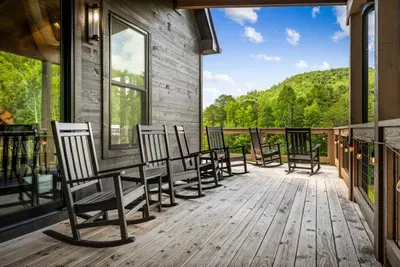 A row of rocking chairs facing the mountains. Most-requested seat on the property, and it costs nothing to sit in it.