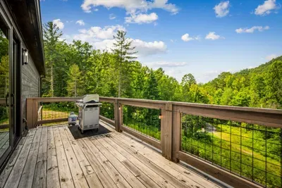 The deck runs the full length of the cabin and ends at the grill. Walk out barefoot, flip burgers, and watch the light drop behind the ridge.