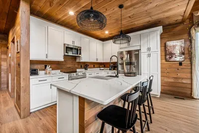 Full chef's kitchen with a quartz island, barstool seating, and stainless appliances. Cook big, because everybody ends up in here anyway.