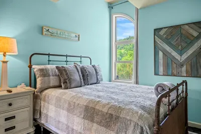 Iron bed, plaid layers, and a window full of mountains