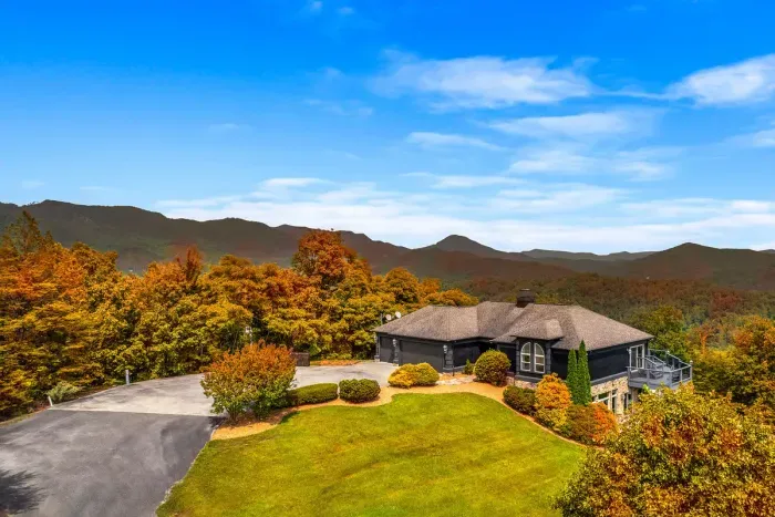 Arrive to sweeping mountain views the moment you pull in — a manicured lawn, attached garage, and layered ridgelines glowing with fall color. Your mountain getaway starts at the driveway.