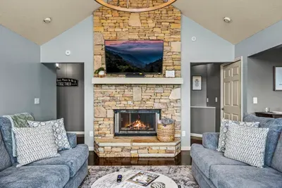 Stone fireplace, TV above, sectionals pulled in close