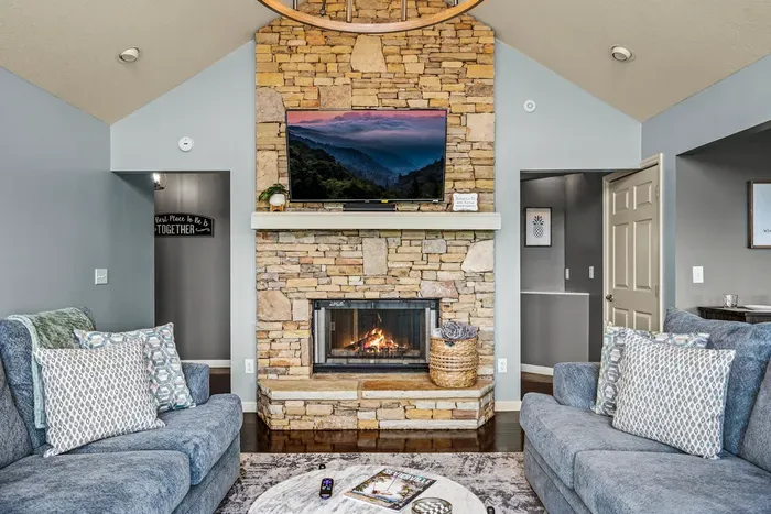 Stone fireplace, TV above, sectionals pulled in close