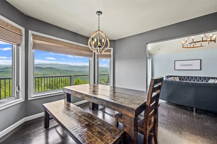 Long farmhouse table under a chandelier, ridgeline out back