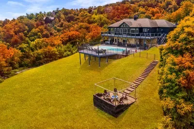 Private pool, hot tub, and hillside fire pit on a mountainside retreat wrapped in fall foliage. Swim by day, gather by the flames at night — room for the whole crew to spread out.