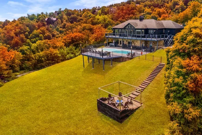 Private pool, hot tub, and hillside fire pit on a mountainside retreat wrapped in fall foliage. Swim by day, gather by the flames at night — room for the whole crew to spread out.