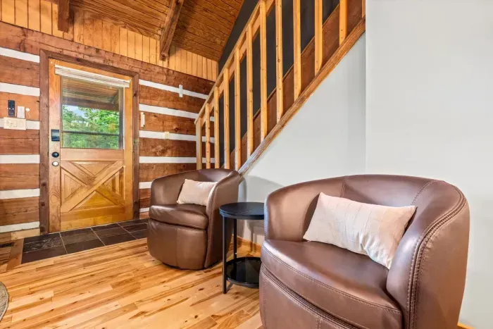Leather swivel chairs tuck beside a barn-door entry and warm log walls — the easy landing spot where you kick off your boots and let the cabin take over. Settle in the moment you arrive.