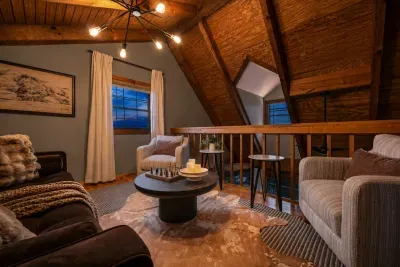 The loft opens into an easy lounge — vaulted ceilings, statement lighting, and seating that invites you to linger long past midnight. The cabin's most quietly upscale corner.