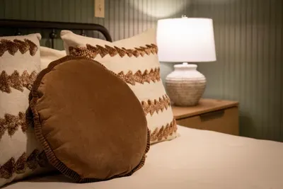 Sink into layers of soft — suede accent pillows, a warm-toned lamp, and bedding made for slow mornings. The little details that make guests book the same room twice.