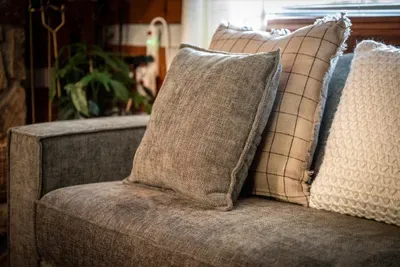 Deep, pillow-piled sofas catch the afternoon light — the spot where books get read, naps get taken, and whole afternoons quietly disappear. Soft landings after a day in the mountains.