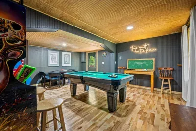 A second full game room up top — pool table, neon glow, and a chalkboard for keeping score — so the fun never has to wait its turn. Two game rooms, zero downtime.