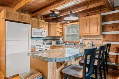 A full kitchen with granite counters, breakfast-bar seating, and warm wood cabinets — cook a real meal, pour the morning coffee, gather around the island. Everything a home cook needs.