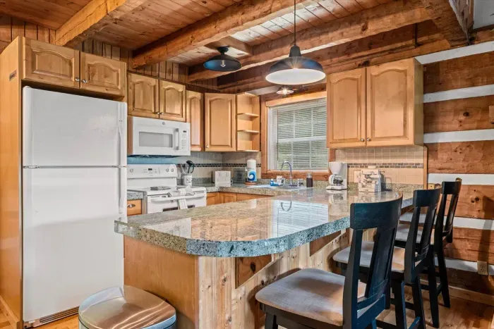 A full kitchen with granite counters, breakfast-bar seating, and warm wood cabinets — cook a real meal, pour the morning coffee, gather around the island. Everything a home cook needs.