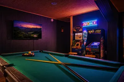 Rack 'em up under a warm pine ceiling — a full-size pool table, classic arcade cabinet, and mountain-view art set the stage for game nights that run late. The room everyone heads to first.