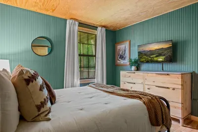 Wake up wrapped in sage-green calm — a plush bed, soft throw, and mountain art make this the easy exhale at the end of an adventurous day. Sleep in; the trail can wait.