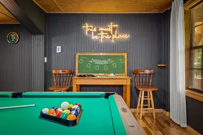 This must be the place" — and the neon agrees. Break a fresh rack on the billiards table, keep score on the chalkboard, and settle in for the kind of night guests still talk about.