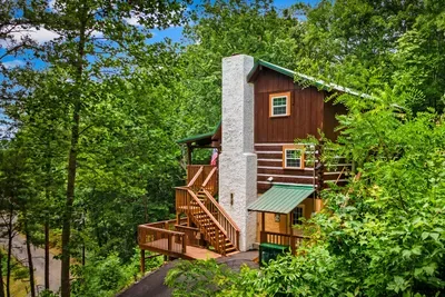 Tucked into the Blue Ridge tree canopy, this cedar cabin rises above it all — wrap-around deck, soaring stone chimney, and pure mountain seclusion waiting for you.