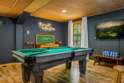Felt, neon, and mountain art set the scene for the cabin's favorite hangout — pool table front and center, room for everyone to crowd around. Where the best nights happen.