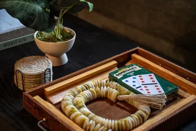 Dominoes ready in a worn wooden box — proof the best nights here don't need a screen. Pour a drink, deal the tiles, and let the laughs run long. Game night, cabin-style.