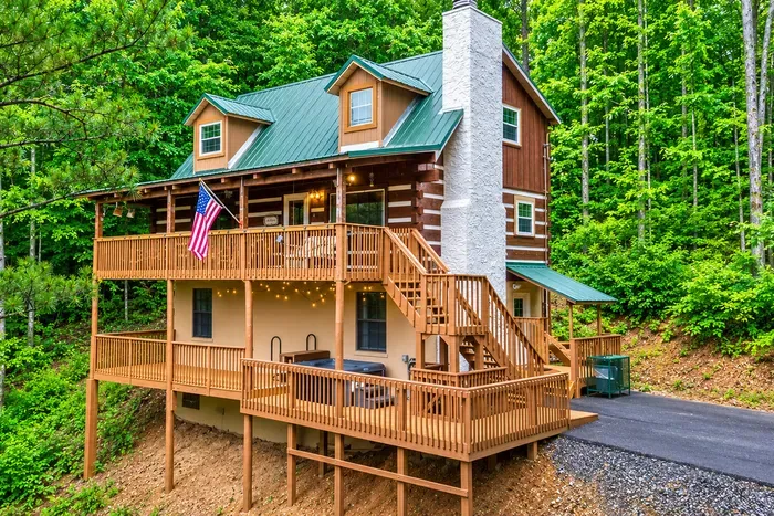 A handcrafted log cabin rising three levels into the canopy — stacked decks, a stone chimney, and porches made for long evenings. Room to spread out and a view that never quits.