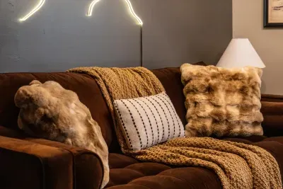 Velvet, faux fur, and a chunky knit throw — this sofa was made for the late-night wind-down with a soft glow overhead. Pure soft-landing comfort after a full day outside.