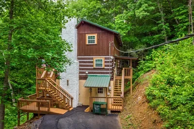 Tucked into the hillside under a green metal roof, this multi-level cabin is your hideaway in the trees — private drive, layered decks, forest on every side. Your escape starts right here.