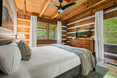 Wake to forest through the windows from a plush king bed wrapped in crisp white linens — log walls, a ceiling fan turning slow, and quiet on every side. Your softest night in the trees.