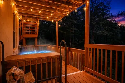 Covered deck, stacked firewood, and a hot tub framed by nothing but trees — your private perch above the forest. Soak under the canopy while the woods do all the talking.