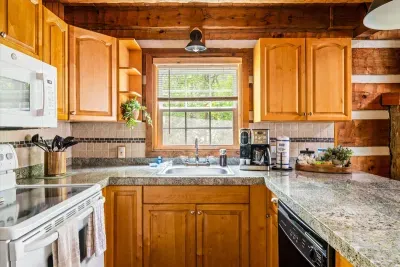 A fully stocked mountain kitchen — granite island, full appliance suite, and that window view making every meal feel like it belongs in a mountain cookbook.