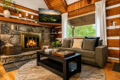 Relax by the stunning stone fireplace in the warm and inviting living room, featuring comfortable seating, soaring vaulted ceilings, and beautiful cabin views. Perfect for unwinding after a day of exploring the Smokies.