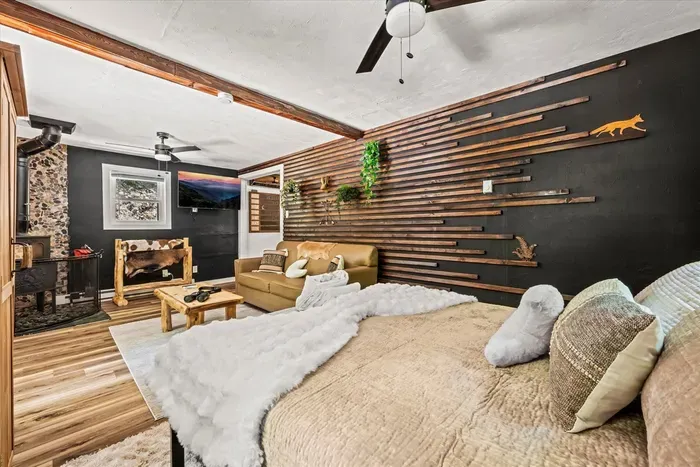 King bed against a handcrafted slat wall, layered in white linens and soft pillows. Windows to the woods, fan turning overhead, and mornings you're in no rush to end.