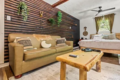 Handcrafted log bench, cushioned sofa, and a bed a few steps away. A room that works for late talkers, early risers, and anyone hiding from the group for an hour.