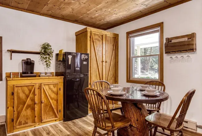 Full kitchen in warm pine with a dining table for four right beside it. Cook what you picked up in town, reheat, or go all out — either way, you'll eat together.