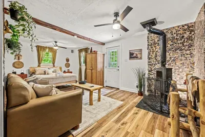 Open living room with a wood stove, handcrafted log furniture, and hardwood floors underfoot. Room to stretch out without ever losing that cabin feeling.