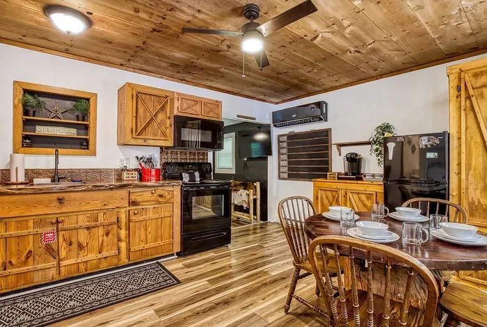 Table set and ready under a pine plank ceiling. Breakfast before the trail, cards after dark, and a kitchen two steps away when someone wants seconds.