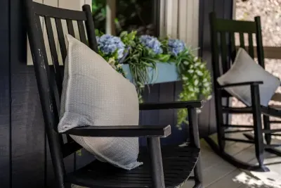 Rocking chairs, hydrangeas, and a pillow already dented from the last guest who couldn't leave. The porch is where most of this stay is going to happen.