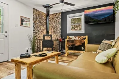 Rock-faced wood stove, deep sofa, and a smart TV for the nights the rain rolls in. Load a log, pull up the blanket, and settle in for a long evening.