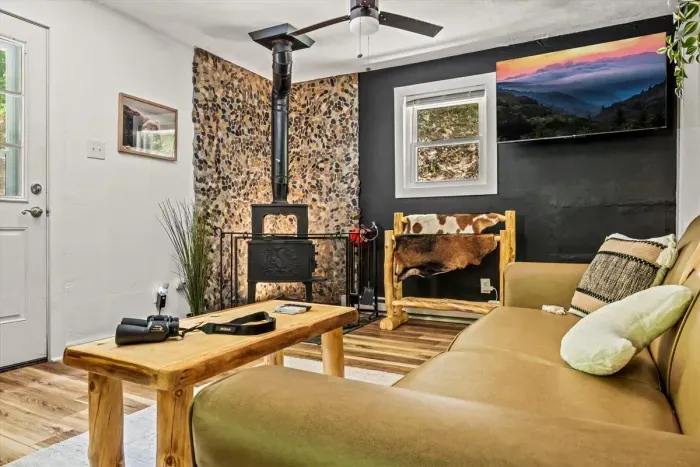 Rock-faced wood stove, deep sofa, and a smart TV for the nights the rain rolls in. Load a log, pull up the blanket, and settle in for a long evening.