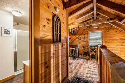 A full bath just off the loft landing, with a walk-in shower and a stained-glass window throwing color across the pine. The kind of detail you notice on day one and remember.