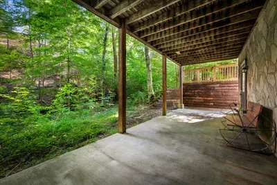 Rain or shine, this covered patio stays usable — rocking chairs, unbroken forest views, and the sound of the creek doing most of the talking for the afternoon.