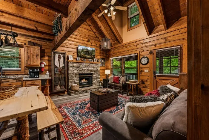 Living and dining flow together beneath vaulted beams — stone fireplace at one end, a farmhouse table at the other. Dinner, cards, and stories without anyone leaving the room.