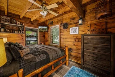 Main-level bedroom with a solid log bed, roomy dresser, and quilted layers made for mountain nights. Cool mountain air, dark skies, and the deepest sleep of the whole trip.