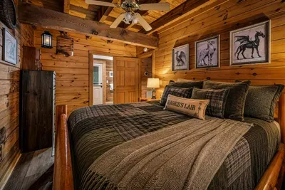 An oversized log bed under warm pine walls, layered quilts turned down, and a reading lamp within arm's reach. Curtains drawn, phone down — ten hours suddenly sounds reasonable.